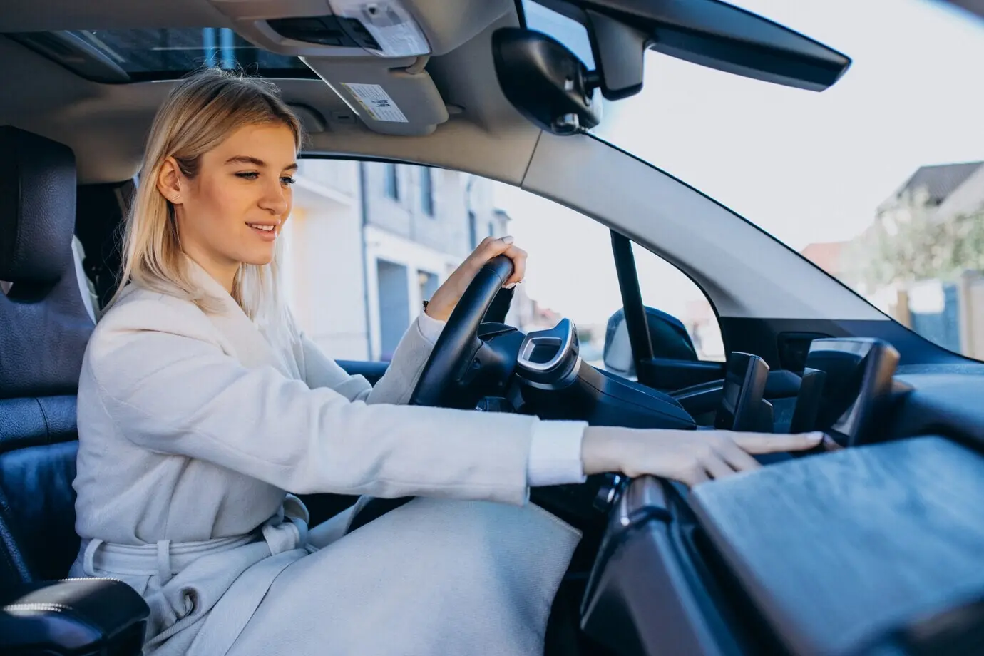 A woman sits inside an electric car while it charges.