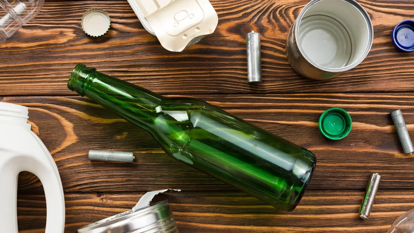An empty glass bottle beside assorted trash.